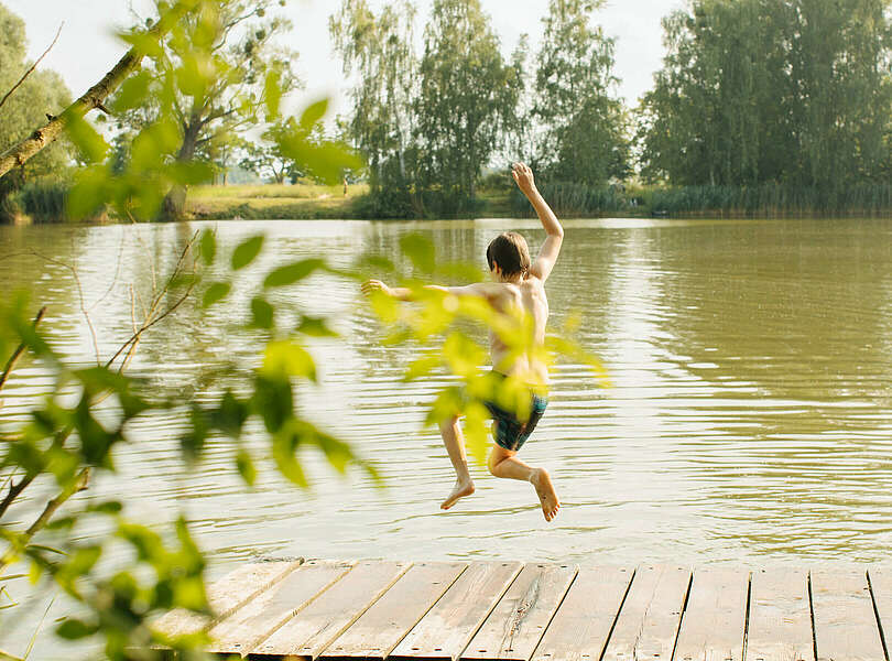 Kind springt in den Badesee