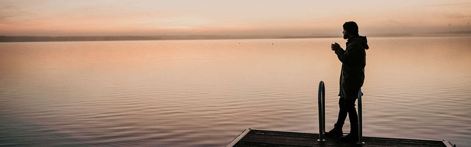 Mann auf einem Badesteg bei Sonnenaufgang ,
        
    

        Foto: TMB-Fotoarchiv/Malte Jäger