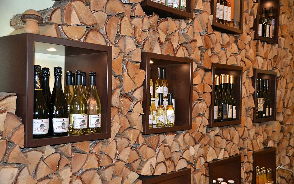 Warme, gelb-braune Töne dominieren das Ladeninnere. Zwischen einzelnen Holzscheiten lagert eine große Auswahl an Weinen und Sekt aus Brandenburg.