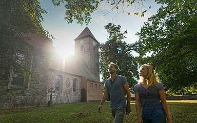 Besucher vor der alten Feldsteinkirche in Menz