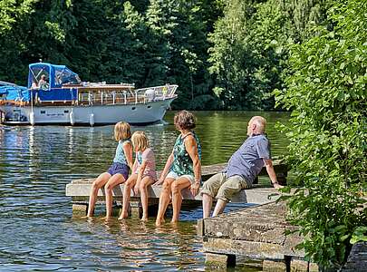 Familie sitzt auf Steg