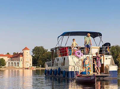 Kormoran vor Schloss Rheinsberg mit Familie am Heck
