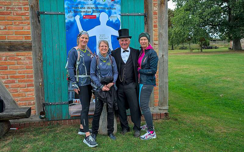Drei sportlich gekleidete Frauen lassen sich vor einer Fotowand mit Theodor Fontane fotografieren.