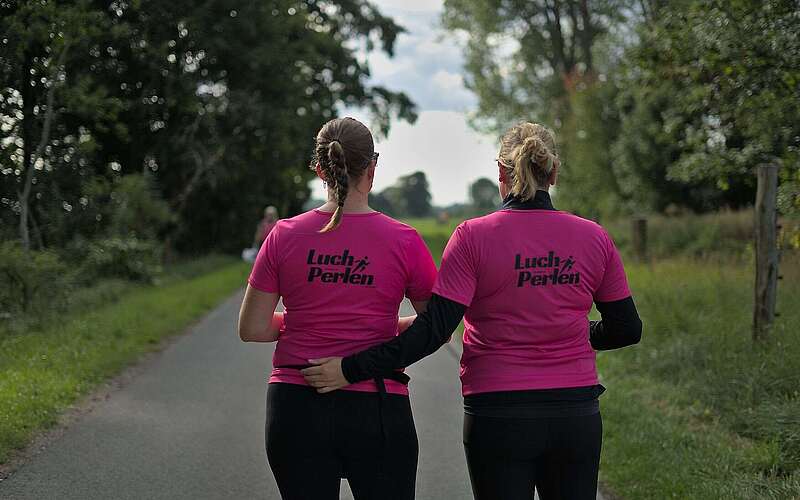 <p>Zwei Frauen tragen knall pinke T-Shirts mit dem Aufdruck "Luchperlen" auf dem Rücken.</p>
