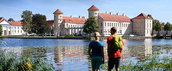 Besucher am Ufer des Grienericksees vor dem Schloss Rheinsberg