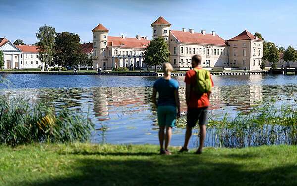 Besucher am Ufer des Grienericksees vor dem Schloss Rheinsberg