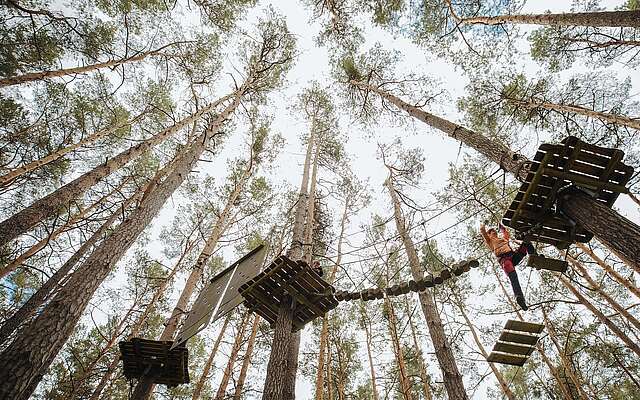Mutter klettert in den Baumwipfeln im Kletterwald Schorfheide