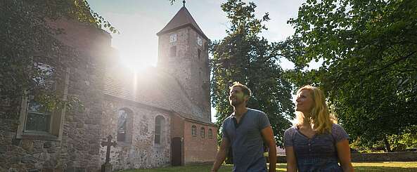 Besucher vor der alten Feldsteinkirche in Menz