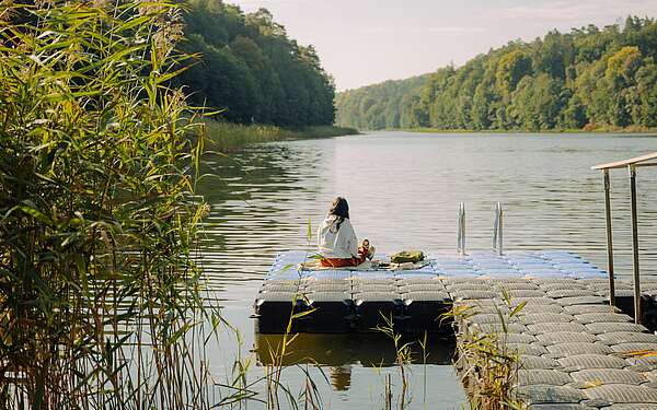 Frau sitzt auf Steg am Gamensee (Wandern auf dem 66-Seen-Weg)