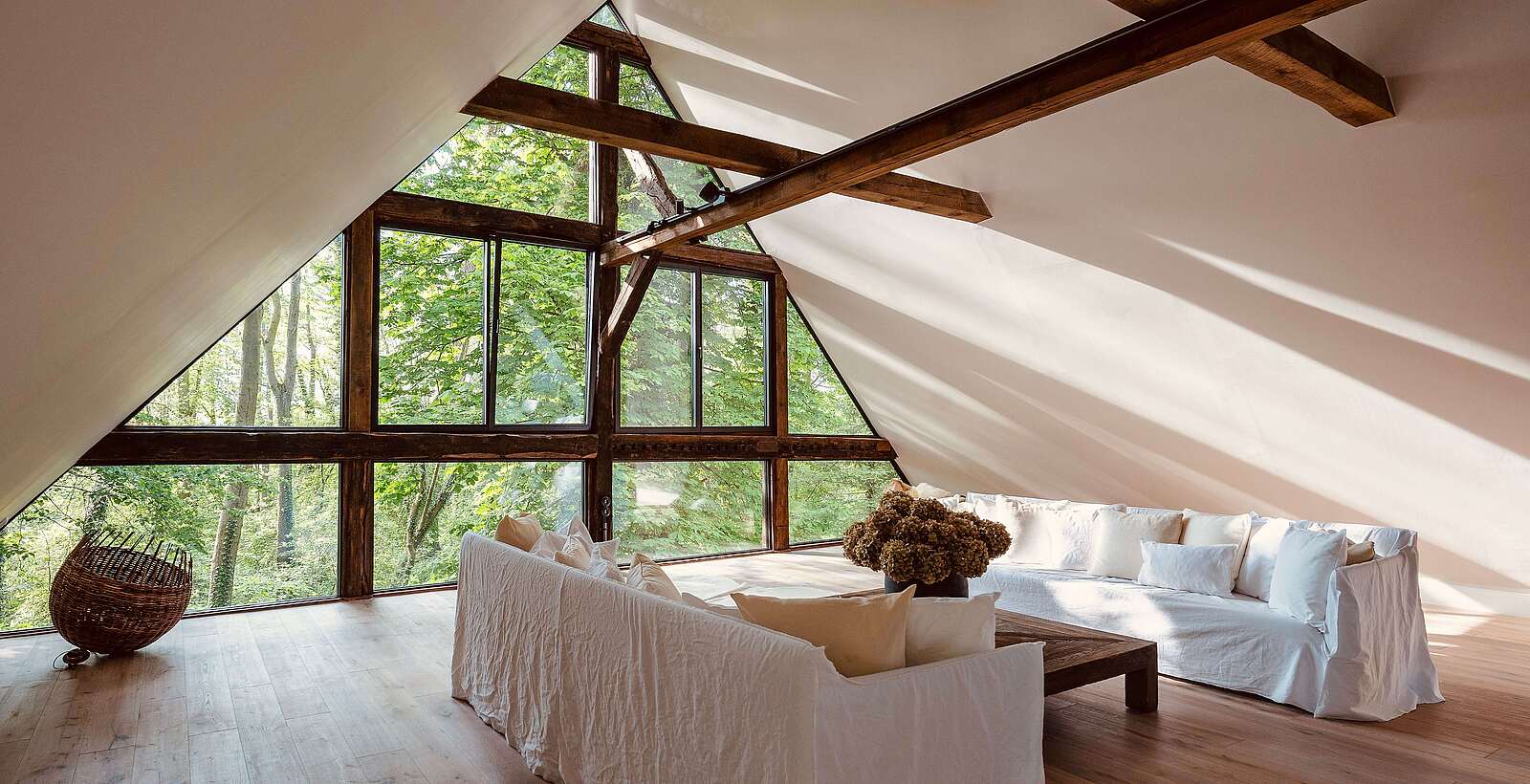 Wohnbereich mit weißen Sofas und Panoramafenster mit Waldblick