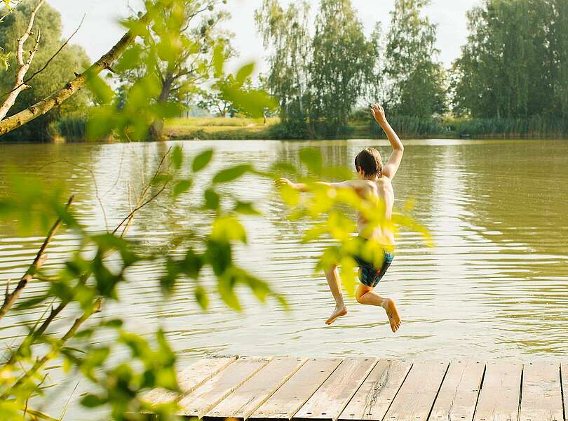 Kind springt in den Badesee