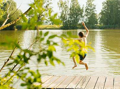 Kind springt in den Badesee