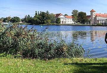 Besucher am Ufer des Grienericksees vor dem Schloss Rheinsberg